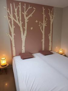 um quarto com uma cama com árvores pintadas na parede em Les appartements sur Pompidou - 7 appartements neufs société selogerametz com em Metz