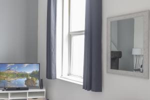 a living room with a television and a window at OPP Plymouth - Large 3 bed, great WIFI and parking! BIG SAVINGS booking 7 nights or longer! in Plymouth