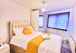 a bedroom with a bed with a yellow blanket and a window at The Dartford Lodge - Free Parking in Kent