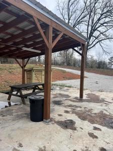a picnic table and a trash can under a wooden pavilion at The Best Buffalo River RV Campsite in Hasty