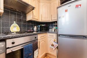 uma cozinha com armários de madeira e um frigorífico de aço inoxidável em Central Camden Flat With Terrace For 4 People em Londres