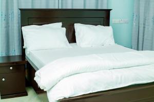 uma cama grande com lençóis brancos e almofadas em Dodoma furnished Apartment em Dodoma