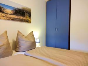 1 dormitorio con 1 cama con almohadas y armario azul en Strandmuschel, en Horumersiel