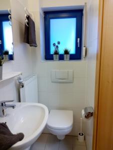 ein Bad mit einem Waschbecken, einem WC und einem Fenster in der Unterkunft Strandmuschel in Horumersiel