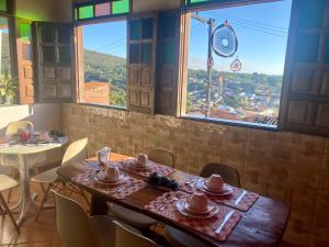 a dining room with a table and chairs and windows at Hospedaria do Tom in Lençóis