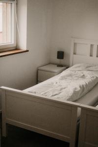 1 cama blanca en un dormitorio con ventana en Ferienwohnung Ziegler en Ebersburg