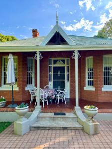 a brick house with a patio with a table and chairs at Heritage Haven in Howick