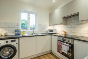 a white kitchen with a washing machine and a sink at Lovely 1 Bed Apartment With FREE PARKING & Garden in Cherry Hinton