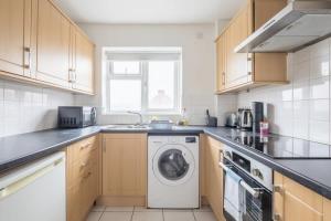 uma cozinha com uma máquina de lavar roupa e um lavatório em Lovely 2 bedroom apartment - ideal location em Cambridge