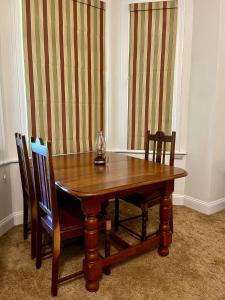 uma mesa de madeira e cadeiras num quarto com cortinas em Heritage Haven em Howick