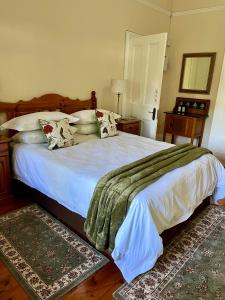 a bedroom with a large bed with white sheets and pillows at Heritage Haven in Howick