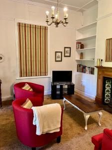 a living room with two red chairs and a coffee table at Heritage Haven in Howick