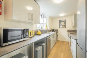 eine Küche mit weißen Schränken und einer Mikrowelle in der Unterkunft Fabulous Large Apartment for 7 - CENTRAL Cambridge in Cambridge