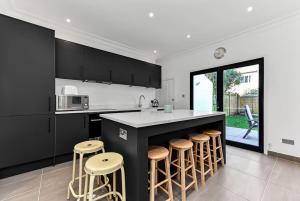 a kitchen with a black island and stools at Beautiful Family Victorian Home in Crystal Palace