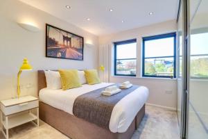 a bedroom with a large bed and windows at Charming and Modern 2 Bedroom House with Parking in Cambridge