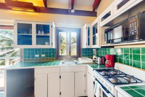 una cocina con armarios blancos y azulejos verdes en Condo #23 @ Beachside Villas en Placencia Village