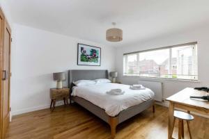 a bedroom with a bed and a desk and a window at Spacious Modern Garden Family Home in Cambridge