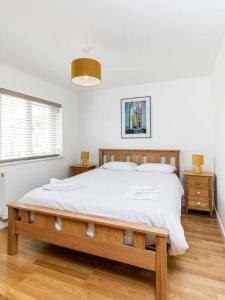 a bedroom with a large bed with white sheets at Spacious Modern Garden Family Home in Cambridge
