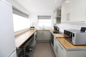 a kitchen with white cabinets and a wooden counter top at Modern and Cosy Flat For 4 in Cherry Hinton