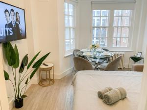 a room with a bed and a dining room with a table at Vibrant 2-Bedroom Flat with Elevator in Marylebone, Close to Hyde Park & Edgware Road in London