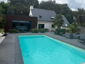 einem Pool mit Holzterrasse und einem Haus in der Unterkunft Villa Cornouaille in Rédené