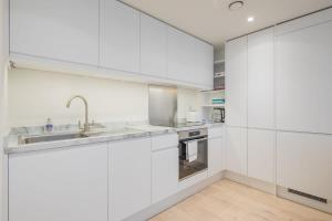 a white kitchen with white cabinets and a sink at Luxury City Centre Apartment in Cambridge