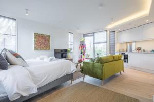 a bedroom with a bed and a green chair at Luxurious Central Apartment with Balcony in Cambridge
