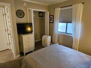 a bedroom with a bed and a television and a window at Beachfront Condo 103 in North Topsail Beach