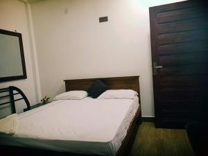 a bedroom with a bed and a brown door at Home Stay Resort in Nilaveli