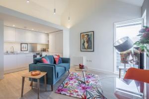 a living room with a blue couch and a kitchen at Luxury City Centre Apartment Stunning River Views in Cambridge