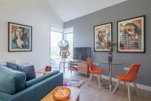 ein Wohnzimmer mit einem blauen Sofa und orangefarbenen Stühlen in der Unterkunft Luxury City Centre Apartment Stunning River Views in Cambridge