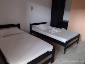 duas camas num pequeno quarto com lençóis brancos em Hotel Tame Real em Tame