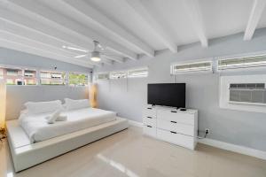 a white bedroom with a bed and a flat screen tv at Coconut Walk To The BeachComfy Beds Firepit Pool in Fort Lauderdale