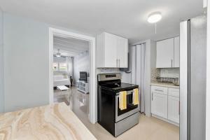 a kitchen with a black stove and white cabinets at Coconut Walk To The BeachComfy Beds Firepit Pool in Fort Lauderdale