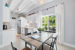 a kitchen with a table and chairs and a large window at The Sandbar Walk To Beach Comfy Beds Firepit Pool in Fort Lauderdale