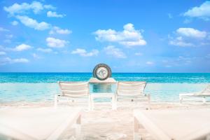 a clock on a beach with chairs and the ocean at Papagayo Beach Hotel in Willemstad