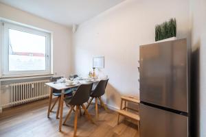 eine Küche mit einem Tisch mit Stühlen und einem Kühlschrank in der Unterkunft FeWo Vogel: City Wohntraum in Bielefeld