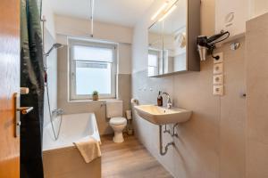 ein Badezimmer mit einem Waschbecken, einer Badewanne und einem WC in der Unterkunft FeWo Vogel: City Wohntraum in Bielefeld