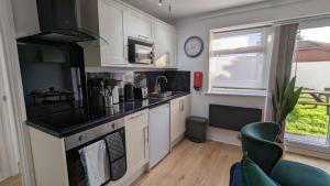 a kitchen with white cabinets and a clock on the wall at OPP Sidmouth - Cosy Coastal Chalet great views! BIG SAVINGS booking 7 days or more! - Dogs by Request Only in Sidmouth