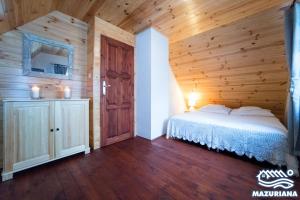 1 dormitorio con 1 cama y pared de madera en Mazuriana - domy wypoczynkowe nad jeziorem, en Skomack Wielki