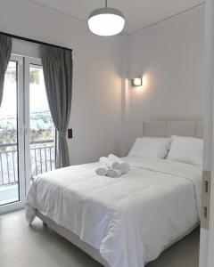 a white bedroom with a large white bed and a window at OpenSea in Chalkida