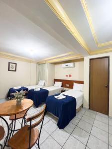 pokój hotelowy z 3 łóżkami, stołem i krzesłami w obiekcie Central Hotel w mieście Campina Grande