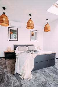 a bedroom with a large bed with two pendant lights at NOI Resort SPA - woda i las in Tęgoborze