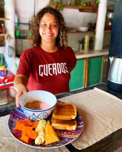 a woman is holding a plate of food with a bowl of soup at Barco Verde Hostel in Holbox Island