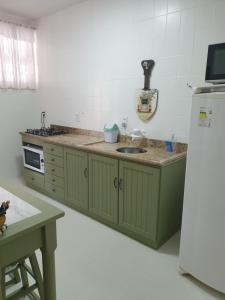 a kitchen with green cabinets and a sink and a refrigerator at Casa Feliz in Campo Alegre