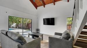 uma sala de estar com dois sofás e uma televisão em Delray Escape Pool Renovated Sleeps 12 em Delray Beach