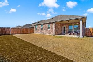 a brick house with a fence and a yard at Sleeps 12~Private Yard~Dog Friendly~Charcoal Grill in Haslet
