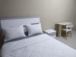 a white bedroom with a bed and a desk at Milestone City - Appartements à louer in Antananarivo
