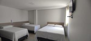 - 2 lits dans une chambre aux murs blancs dans l'établissement ESPETO DE OURO HOTEL, à Ouricuri