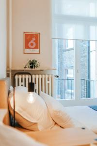 um quarto com uma cama com almofadas brancas e uma janela em namastay! Eleganz mit Blick auf dem Wasserturm em Mannheim